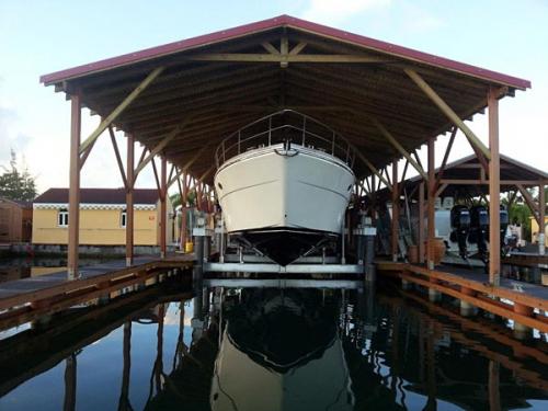 Front view of white boat on an 80,000 pound 8-Post Boat Lift under a wooden awning in Guadalupe.