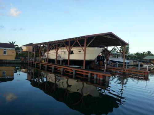 White boat on an 80,000 pound 8-Post Boat Lift under a wooden awning in Guadalupe.