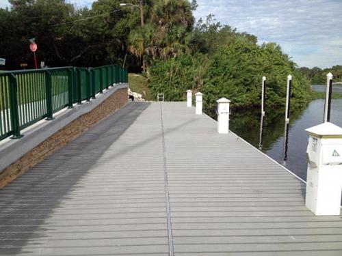 wide floating aluminum dock beside large cement walkway with railing
