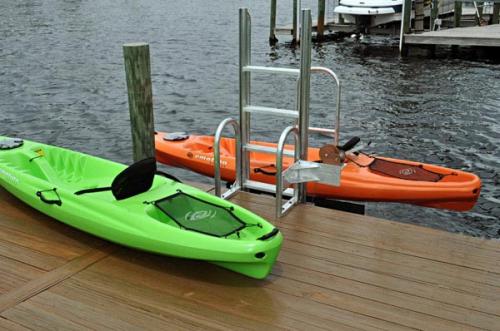 green kayak on dock overlooking orange kayak in a kayak launch
